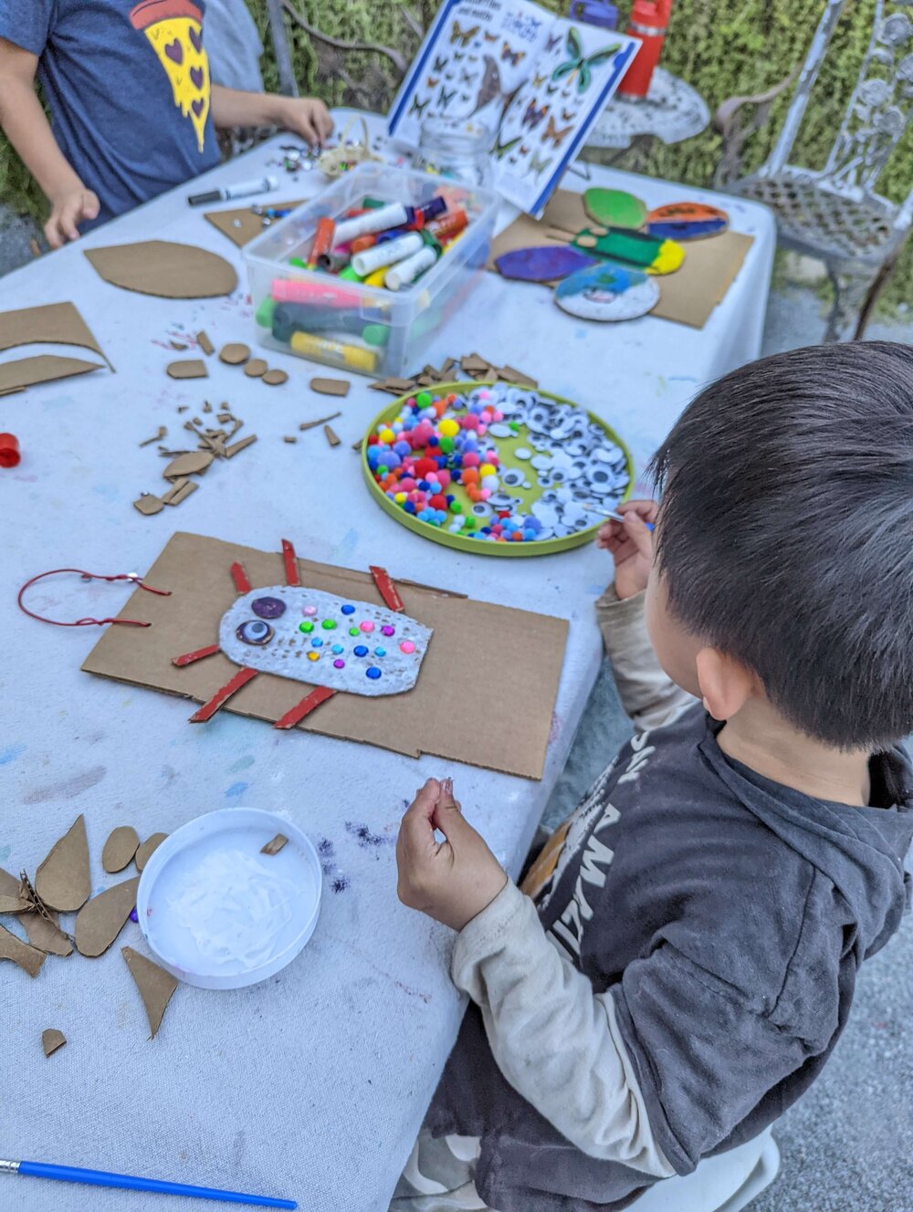 A young child painting independently at an outdoor table at Pachis art studio, Linda Vista, San Diego